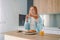 Portrait of a hungry young woman eating wholesome sandwich, having tasty breakfast in a kitchen at home in the morning