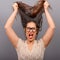 Portrait of a hysterical woman pulling hair out against gray background