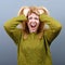 Portrait of a hysterical woman pulling hair out against gray background