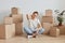 Portrait if sick tired woman wearing white T-shirt sitting on the floor near cardboard boxes with personal pile, being tired