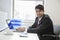 Portrait of an Indian businessman writing on paper at desk in office