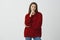 Portrait of indifferent unimpressed attractive feminine european female in stylish loose sweater, holding fingers on