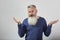 Portrait of indignant mature gray-haired bearded man on gray background, selective focus