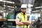 Portrait of industrial engineer worker wearing helmet and safely glasses standing with arms crossed, holding wrench and working at