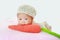 Portrait of infant baby on white background lying on pink pillow decorate with carrot Knitting