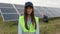 Portrait of inspector engineer woman in working clothes standing by solar panel field. Clean energy production. Green