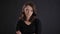 Portrait of irritated young brunette woman with crossed arms watching with annoyance into camera on black background.