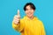 Portrait Of Japanese Teen Guy Gesturing Thumbs Up, Blue Background