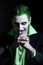 Portrait of a joker. Makeup for Halloween. Crazy image of a man in a green shirt with green hair