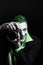 Portrait of a joker. Makeup for Halloween. Crazy image of a photographer man in a green shirt with green hair with