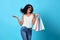 Portrait of an jovial beautiful woman holding shopping bags isolated on blue background