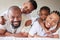 Portrait of a joyful african american family lying on each other on a bed in a bedroom. Black parents spending quality