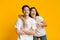 Portrait of joyful asian couple posing over yellow background