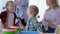 portrait of joyful boy with down syndrome having fun dancing with roller in blue paint with parents and sister