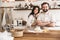 Portrait of joyful couple making homemade pasta of dough while cooking together in kitchen at home