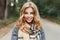 Portrait of a joyful cute young woman with a smile with blue eyes in an elegant coat with a checkered stylish scarf