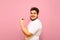 Portrait of a joyful fat guy on a pink background, emotionally happy to win and looking into the camera with a smile on his face.