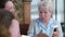 Portrait of joyful female retiree talking laughing pointing at photo telling stories to granddaughter and daughter at