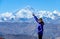 PORTRAIT: Joyful female traveler points at the windswept peak of Mount Everest.