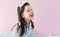 Portrait of a joyful little girl in pajama enjoying confetti from white feathers while playing in the bed, on pink background. A