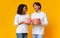 Portrait of joyful multiracial couple with popcorn buckets in hands