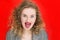 Portrait of joyful pretty woman over red background, emotional curly girl showing tongue at the camera. Emotion facial