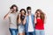 Portrait of joyful young group of friends with funky sunglasses standing in a studio.