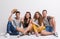 Portrait of joyful young group of friends sitting on the ground in a studio.