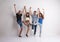 Portrait of joyful young group of friends standing in a studio, lifting legs.