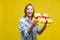 Portrait of joyous beautiful woman in denim shirt standing with opened gift box. studio shot  on yellow background