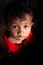 Portrait of a Khmer little boy with spot light pointing on him, cute black eyes looking up at camera