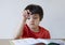 Portrait Kid boy holding black pen sitting alone and looking down with bored face ,Lonely child looking d down at table with sad