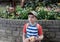 Portrait kid holding plush toy sitting in the garden,Happy boy looking out with smiling face,Child wearing hat and carrying