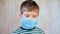 Portrait of kid wearing medical protective facemask in public place during coronavirus and flu outbreak. Covid-19