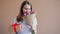 Portrait of lady with bunch of flowers and gift box smiling on beige background