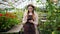 Portrait of lady using tablet in greenhouse touching screen counting plants