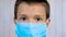 Portrait Latin Smiling Boy in Protective Mask. Child with Black Eyes in Blue Disposable Mask Looking at the Camera no