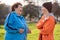 Portrait of laughing elder woman and girl talking together. Park on the background. International Day of Older Persons