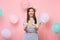 Portrait of laughing fascinating young woman in straw summer hat and blue dress holding credit card on pastel pink