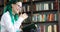 Portrait of laughing girl student with green dreadlocks reads book in library.