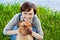 Portrait of laughing happy young woman in denim overalls hugging her red cute dog Shar Pei in the green grass in sunny day