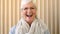 Portrait of a laughing older woman looking happy inside an empty room. Face closeup of an elderly female with glasses in