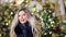 Portrait of laughing pretty woman posing surrounded by snowflakes at Christmas tree lights bokeh