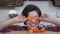 Portrait of laughing and smiling girl putting in front of the eyes orange slices of carrot on the background of modern