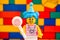 Portrait of Lego birthday girl with lollipop against colour brick wall background