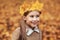 Portrait liitle cute girl with crown of leaves in autumn park