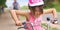 Portrait of a litte girl in a pink safety helmet driving her bike.