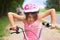 Portrait of a litte girl in a pink safety helmet driving her bike.