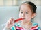 Portrait of little Asian child girl feeding liquid medicine with a syringe by self