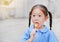 Portrait of little Asian child girl in school uniform enjoy eating tasty sausage